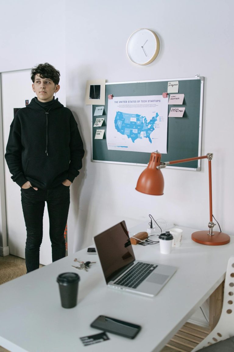 Man in Black Jacket Standing Near White Wall